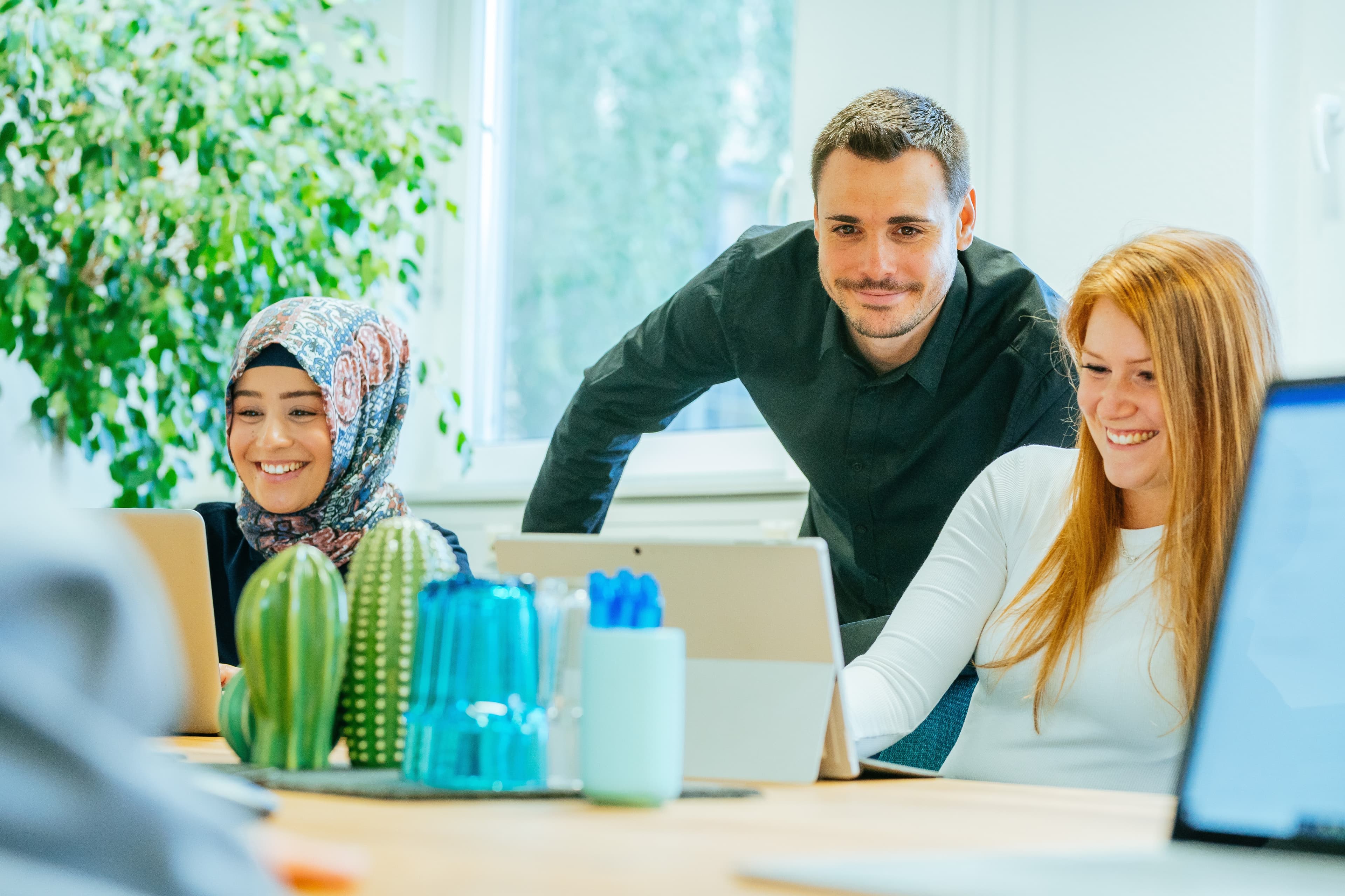 Drei Personen arbeiten gemeinsam an einem Arbeitsplatz