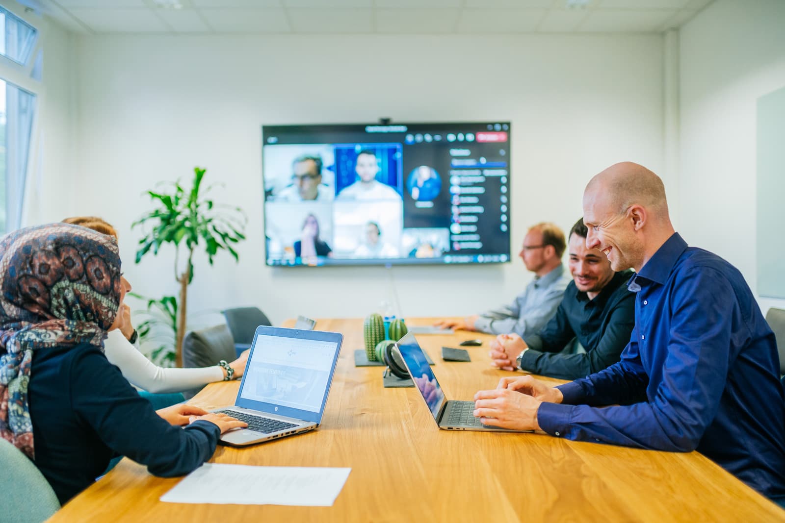 Besprechung im NMS-Meetingraum mit laufender Videokonferenz auf dem Wanddisplay